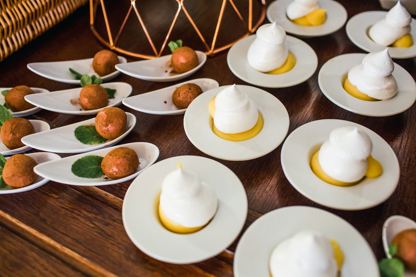 Individual chocolate truffles and lemon tarts on a wooden table.