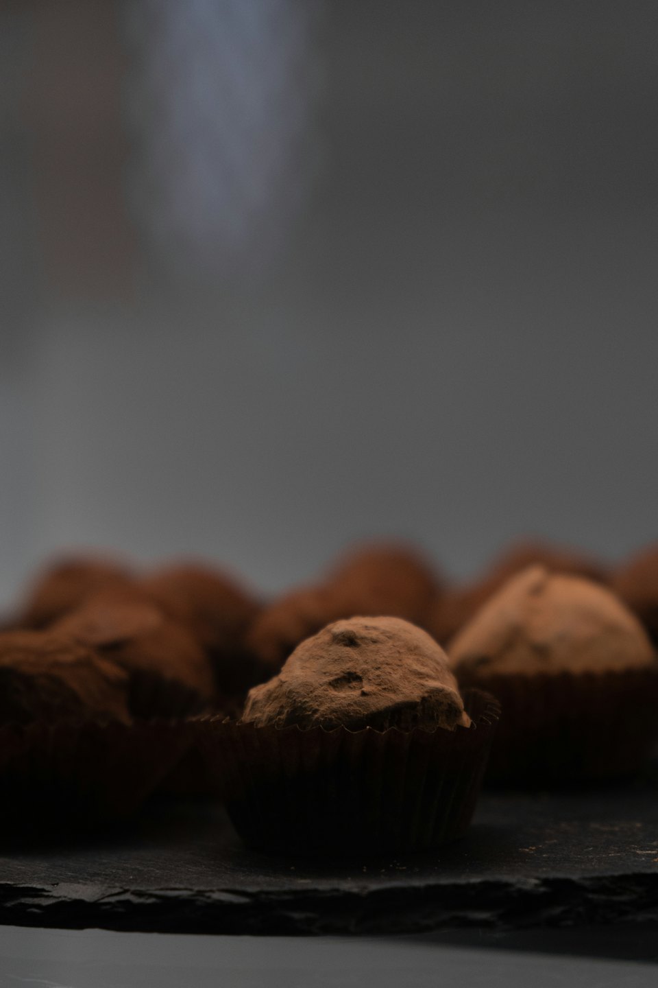 Cocoa dusted chocolate truffles on a slate surface.